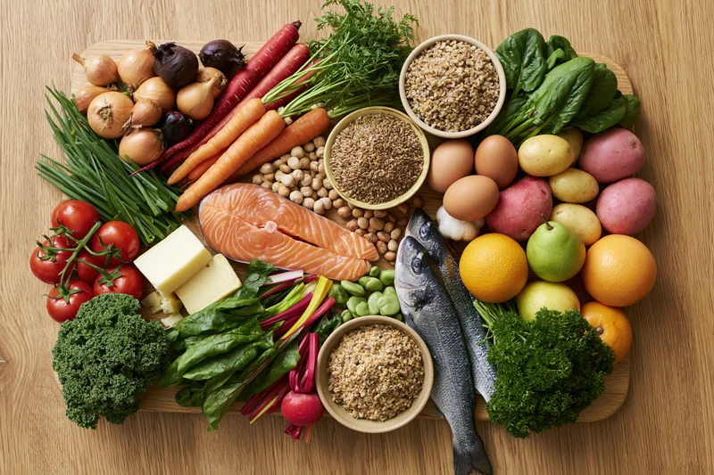 Diverse whole foods arranged in a loose square on a wooden board