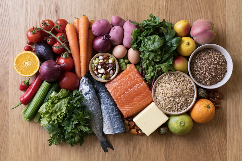 Diverse whole foods arranged in a loose square on wooden surface
