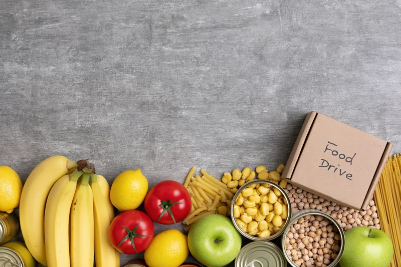 Food drive donation items arranged along the bottom of a gray surface with copyspace above