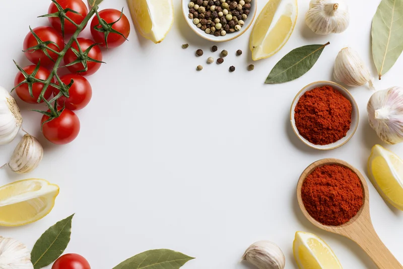 Fresh cooking ingredients arranged as a border frame on white surface with copyspace