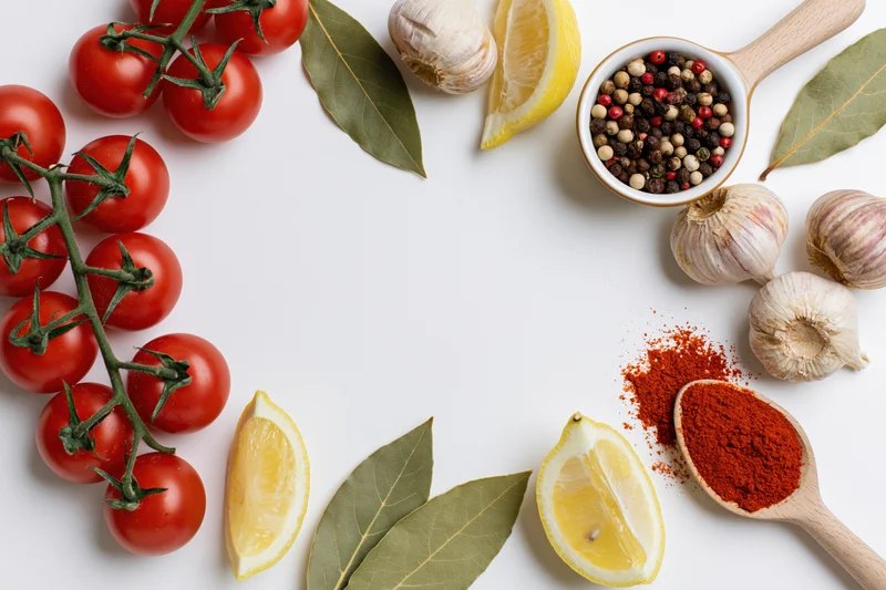 Fresh cooking ingredients arranged as a border on white surface with copyspace