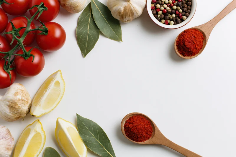 Fresh cooking ingredients arranged as a border on white surface with copyspace