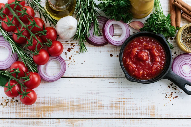 Fresh cooking ingredients arranged in a border on a white wooden table with copyspace