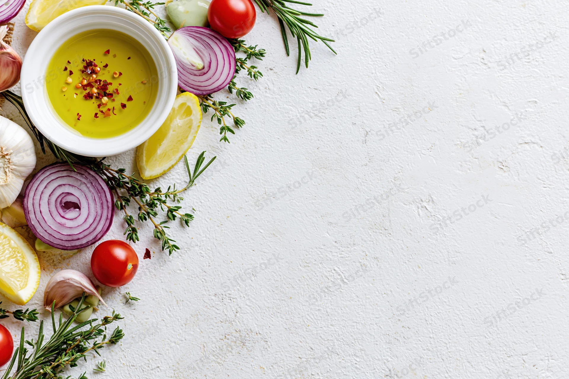 Fresh salad dressing ingredients arranged along the left side of a white textured surface