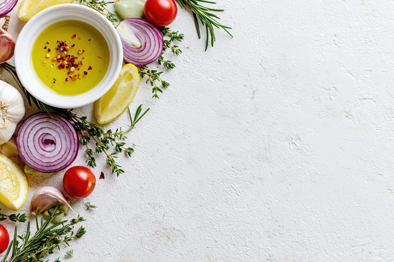 Fresh salad dressing ingredients arranged along the left side of a white textured surface