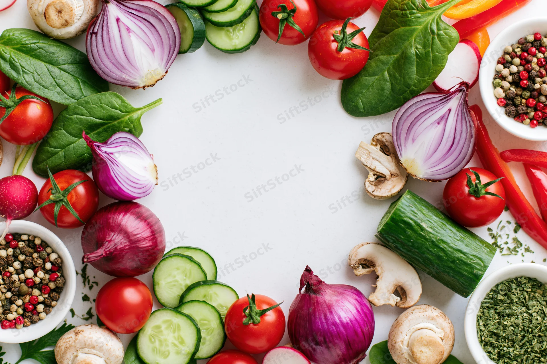 Fresh vegetables arranged in a border frame on white surface with copyspace in center