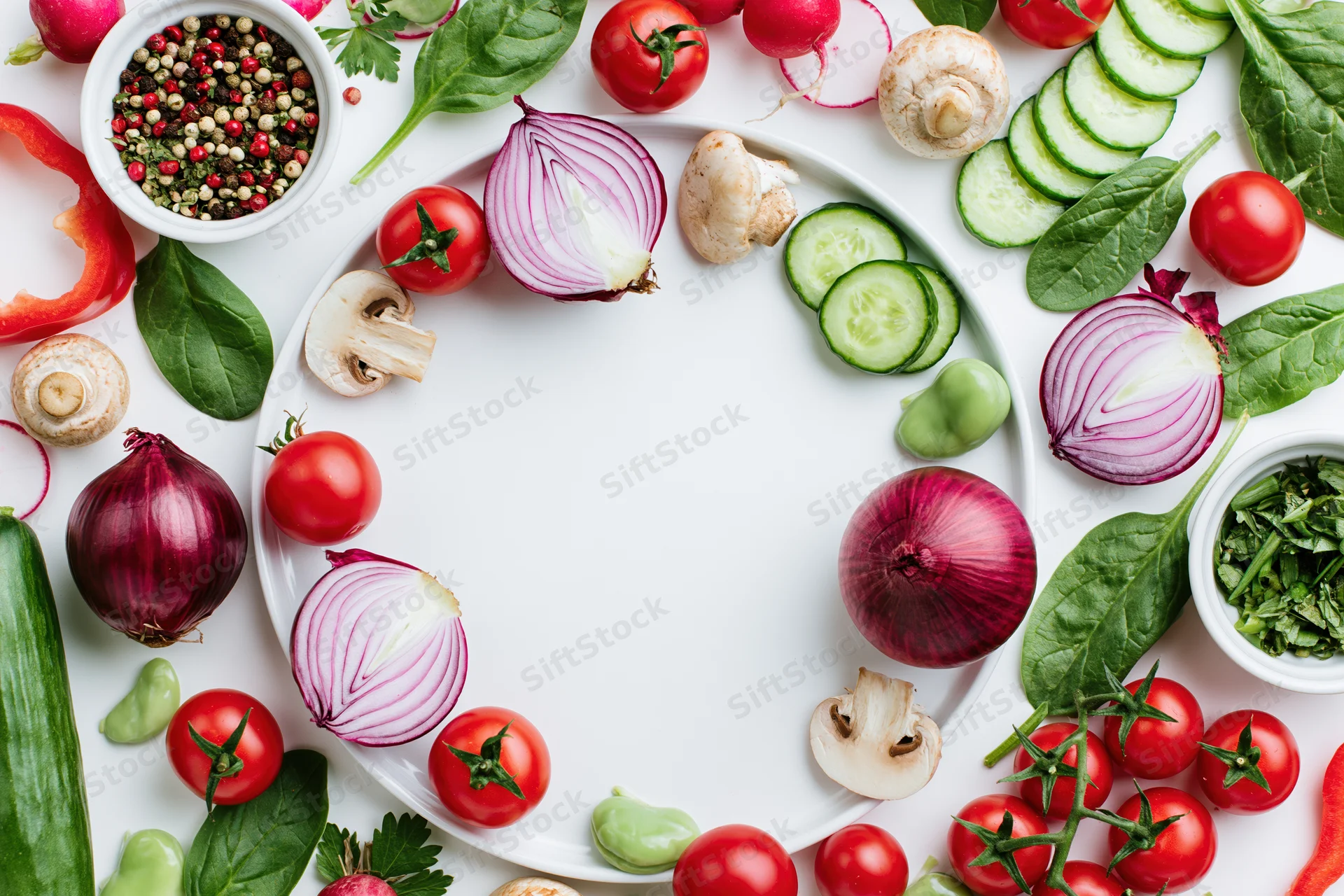 Fresh vegetables arranged in a circular border around a white plate on a flat surface