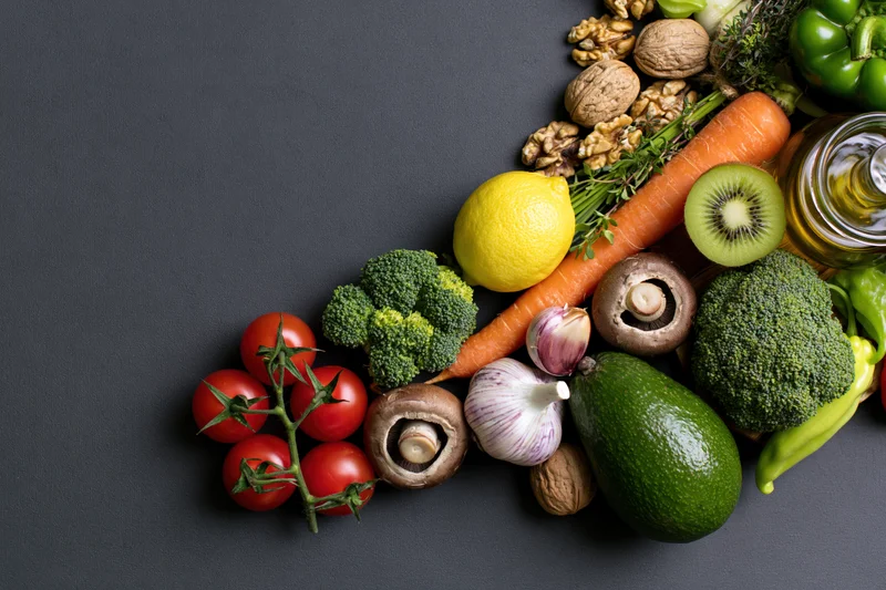 Fresh vegetables fruits and nuts arranged in a diagonal line on dark surface with copyspace