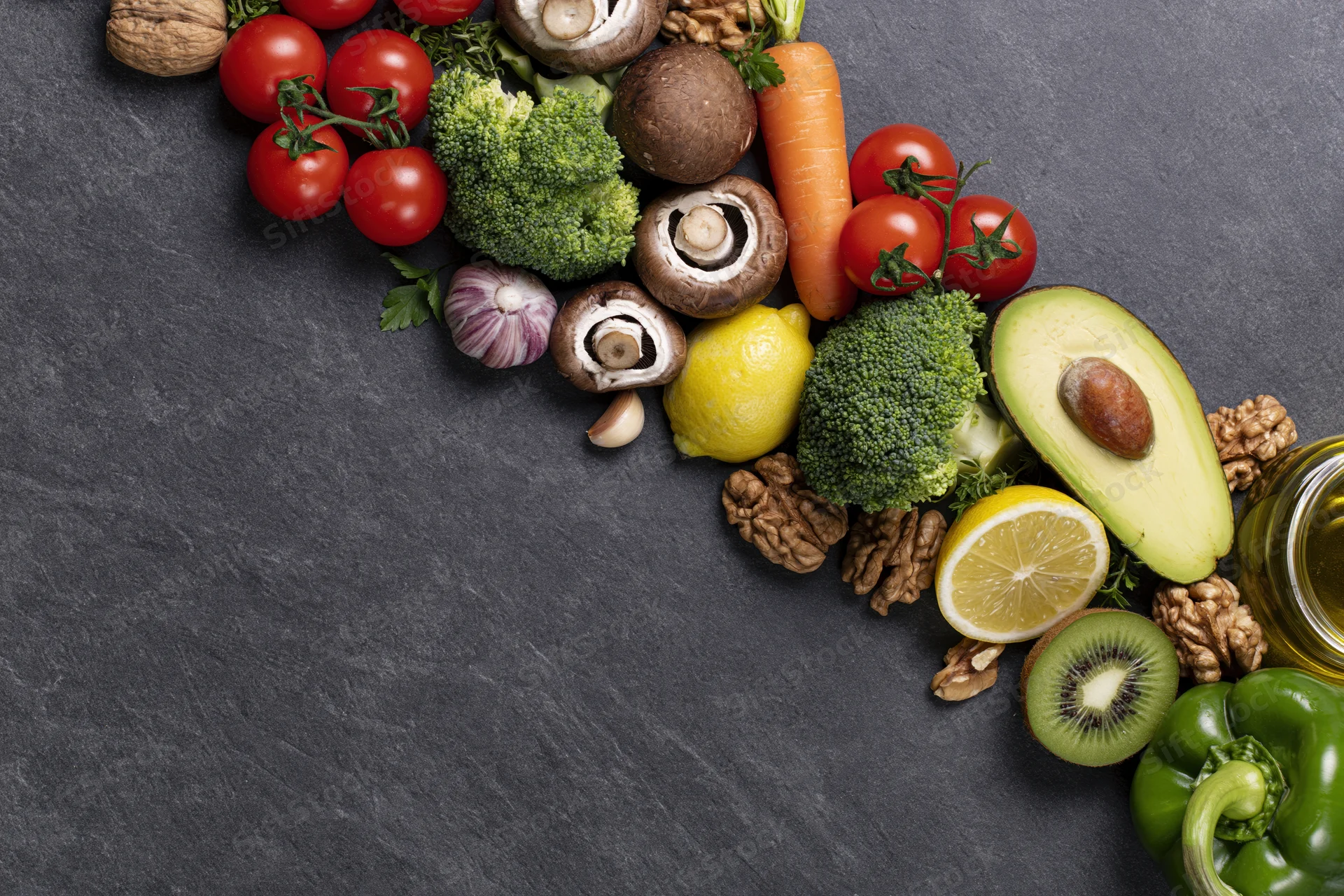 Fresh vegetables fruits and nuts arranged in a curve on dark slate surface