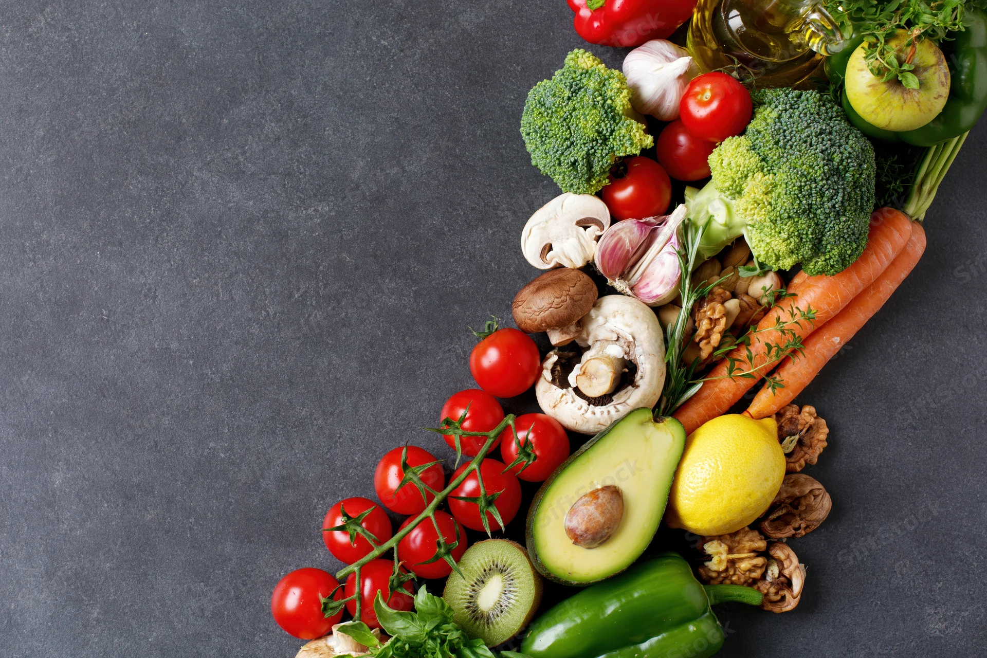 Fresh vegetables fruits and nuts arranged in a diagonal line on dark surface