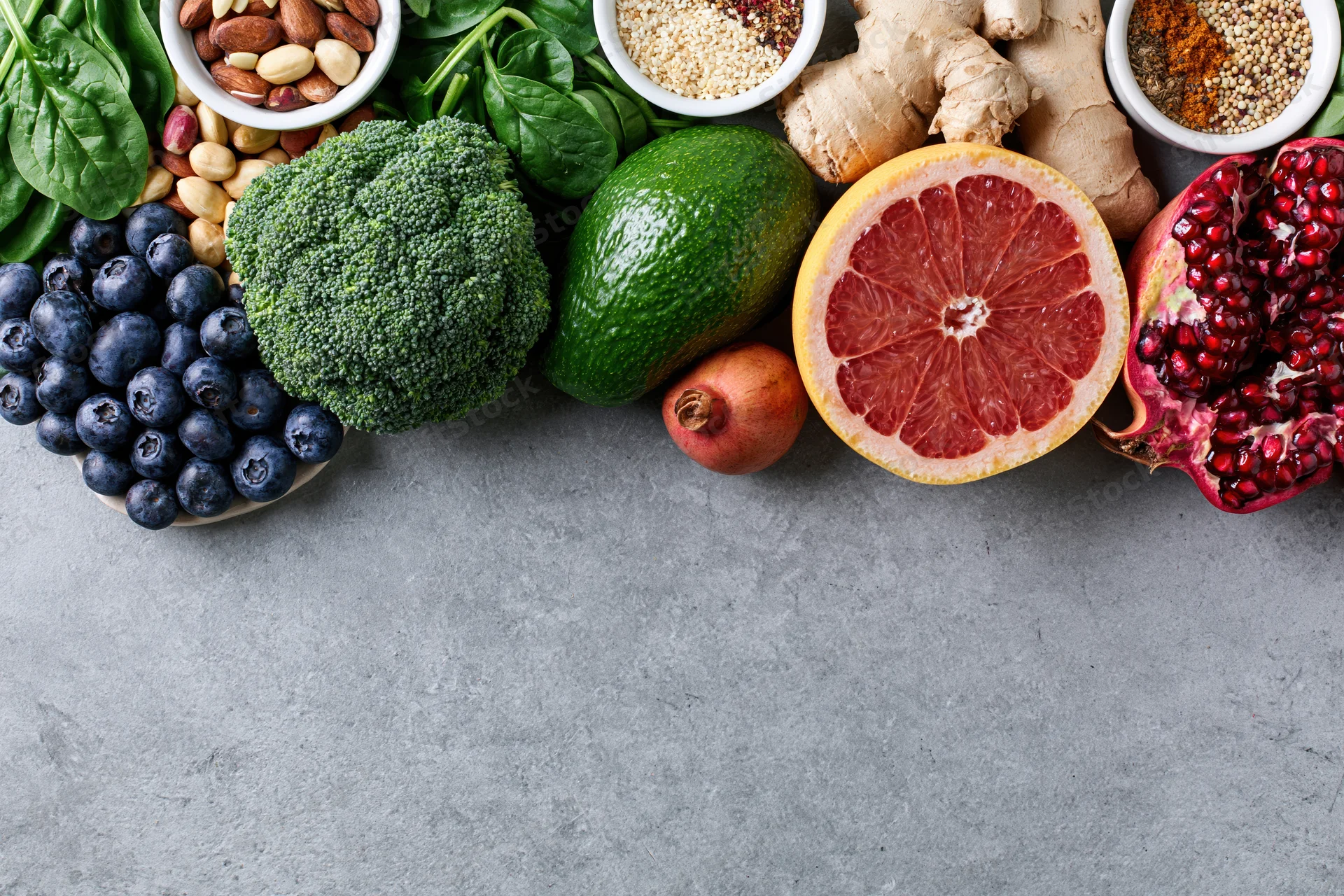 Fresh fruits vegetables nuts and seeds arranged in a flat lay on a gray surface with copyspace