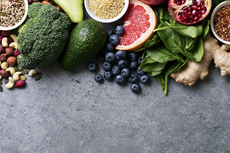 Fresh vegetables fruits nuts and seeds arranged on gray countertop in flat lay view with copyspace