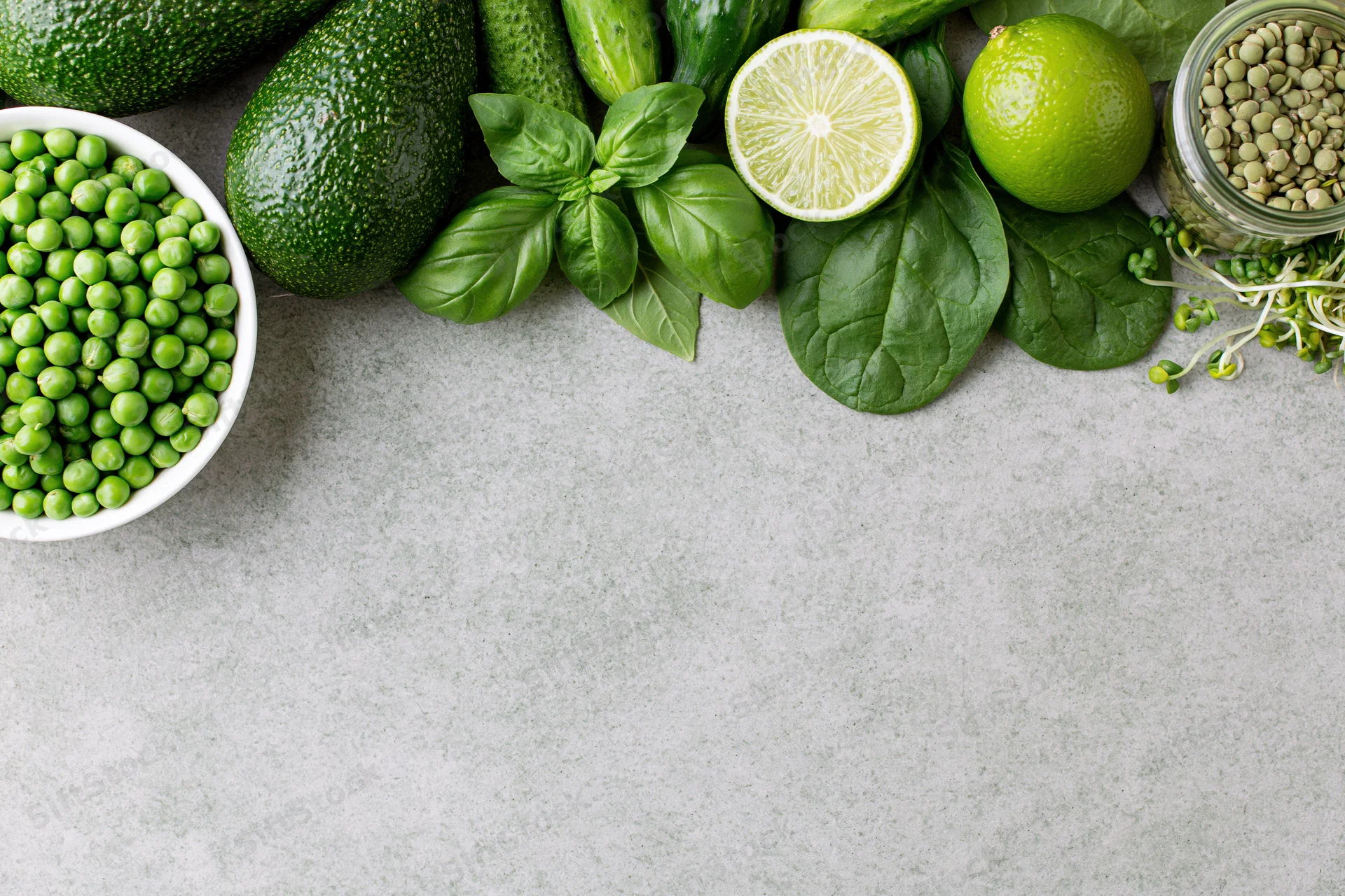 Green vegetables and ingredients arranged along top edge of countertop with copyspace below