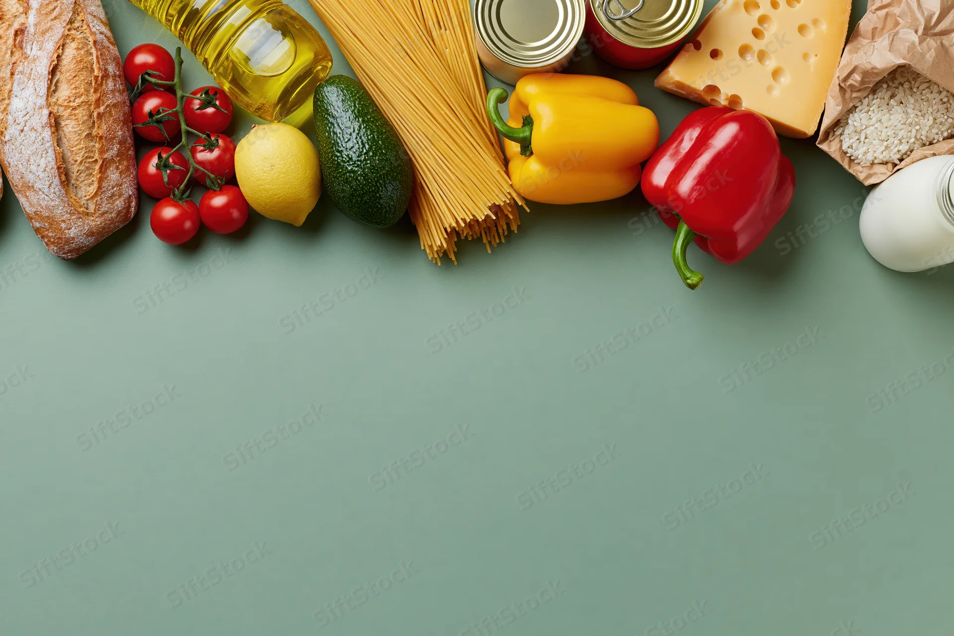 Grocery staples arranged along the top edge of a green surface with copyspace below