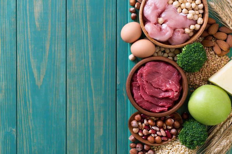 High-protein foods arranged along the right edge of a blue wooden surface