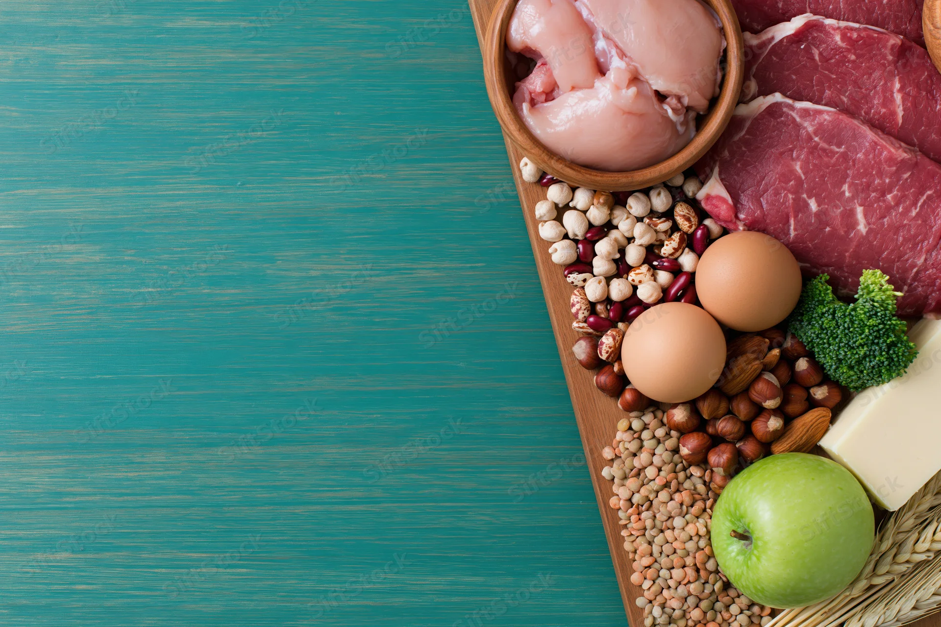 High-protein foods arranged along the right edge of a wooden board on a blue surface