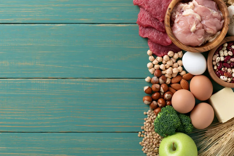 High-protein foods arranged along the right edge of a teal wooden table