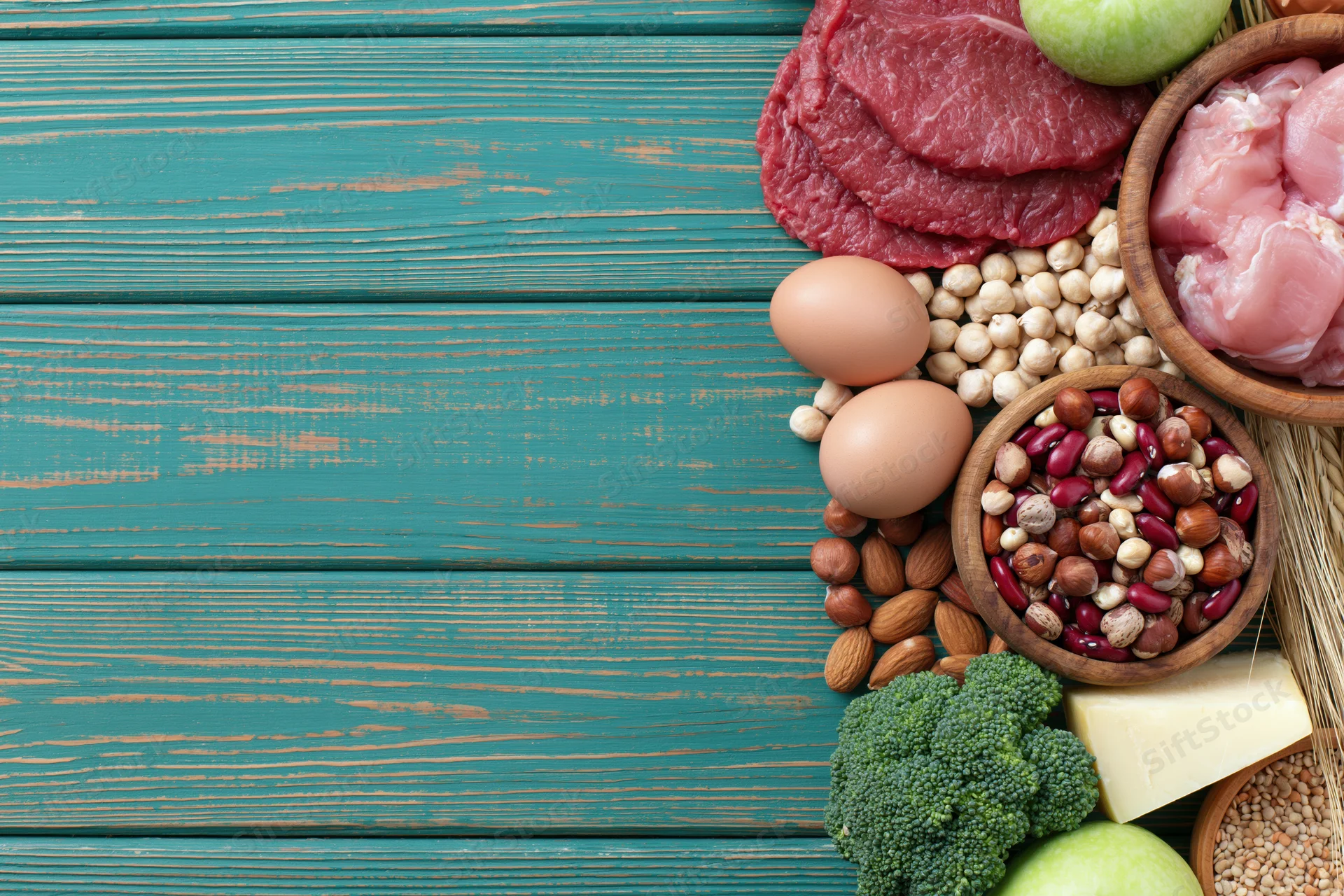 High-protein foods arranged along the right edge of a teal wooden table