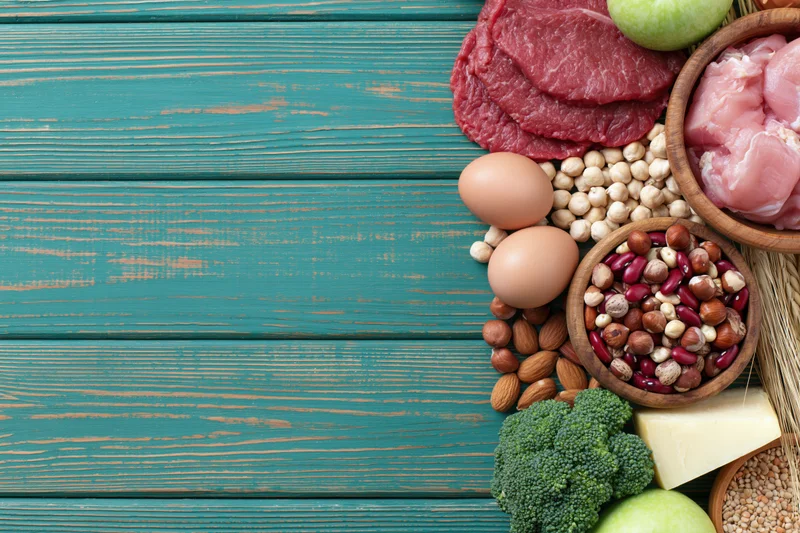 High-protein foods arranged along the right edge of a teal wooden table