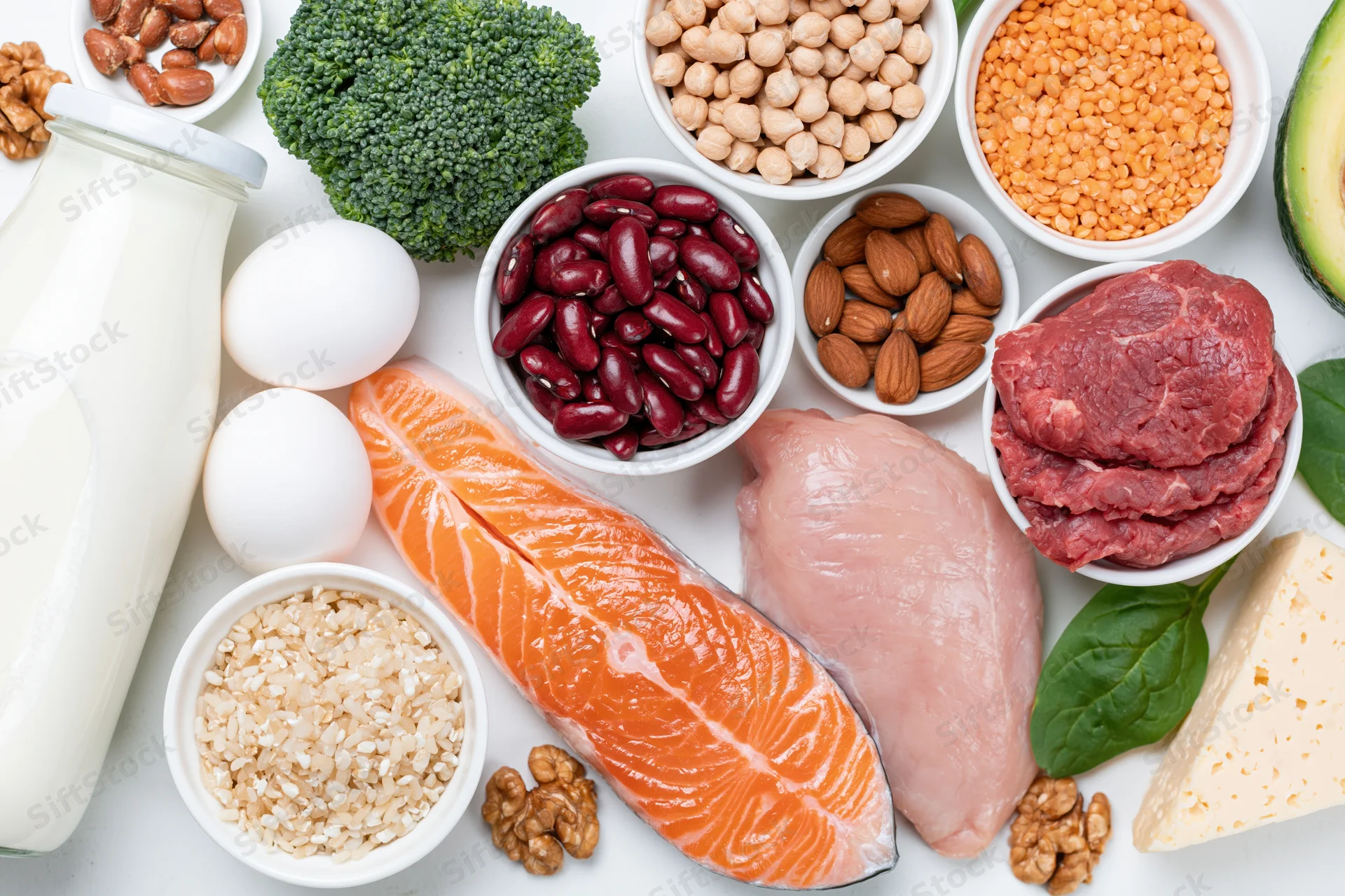 High-protein foods arranged in bowls and on a white surface in a flat lay composition