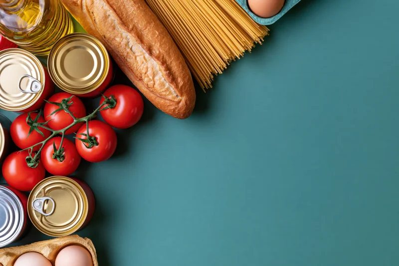 Pantry staples arranged along left edge of teal surface with copyspace on right