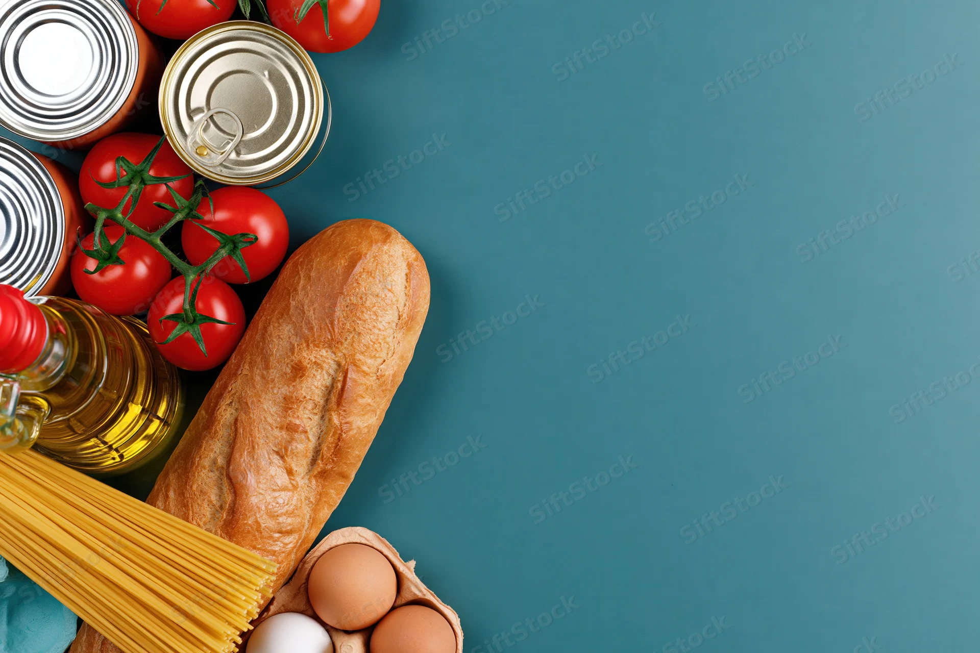 Pantry staples arranged along left edge of teal surface with copyspace