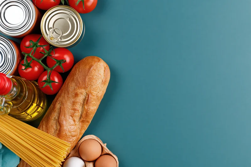 Pantry staples arranged along left edge of teal surface with copyspace