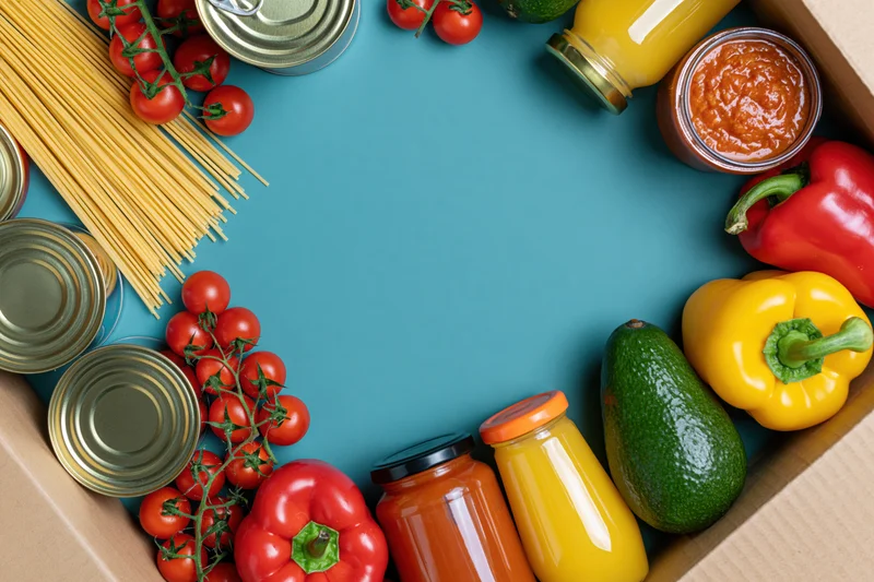 Assorted groceries arranged in a box frame on blue surface