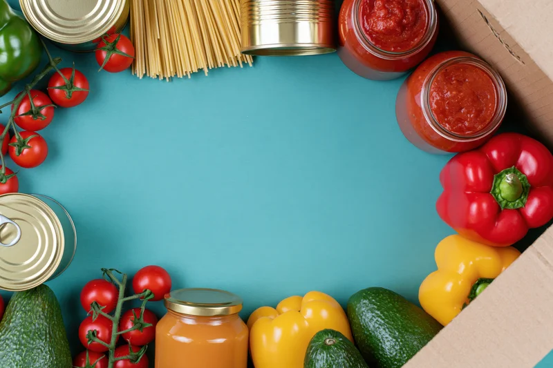 Assorted groceries arranged in a border around a blue surface with copyspace in center
