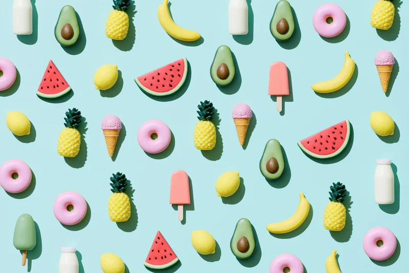 Scattered summer fruits and desserts on a light blue flat lay surface