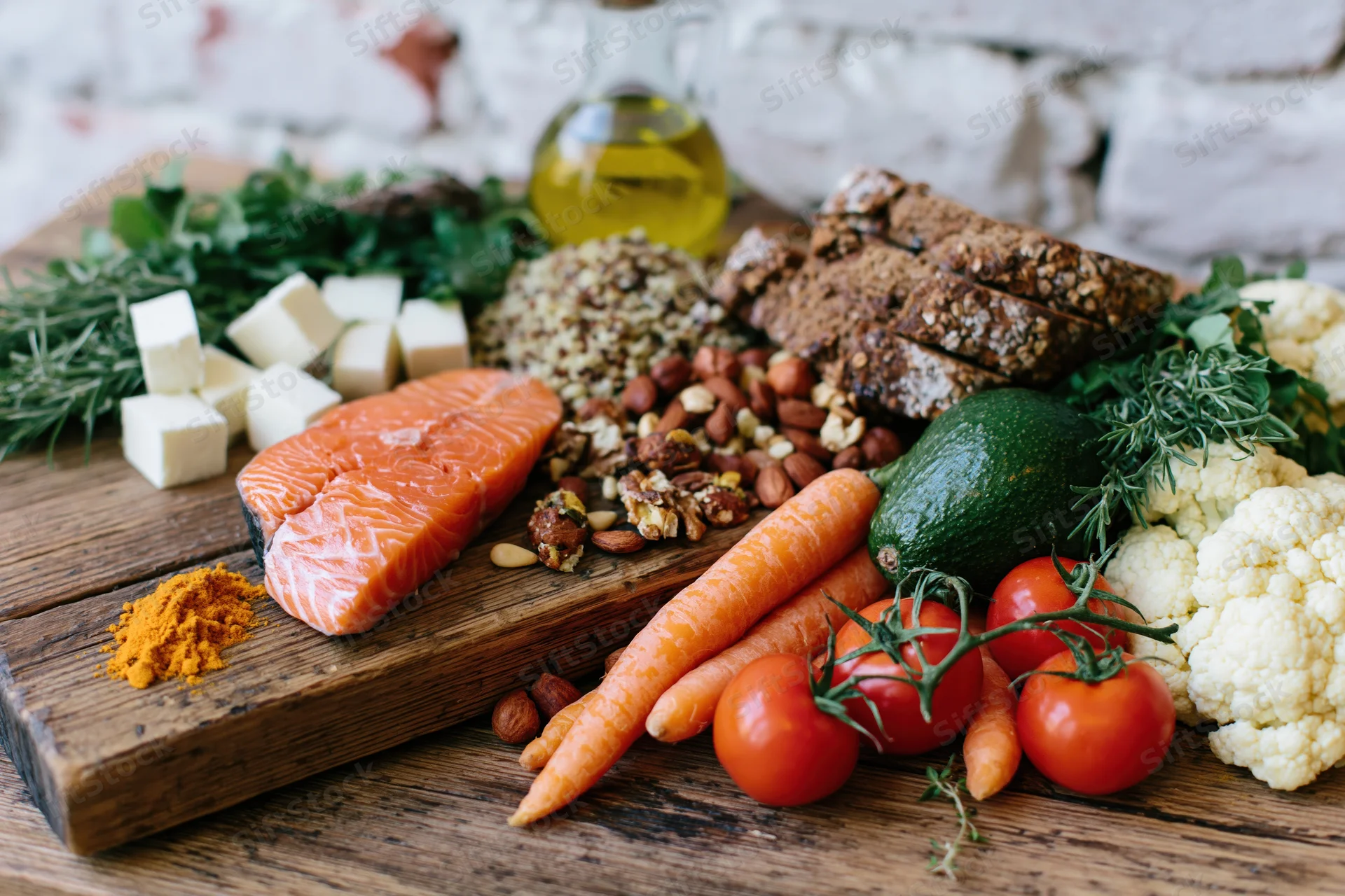 Salmon and vegetables arranged on a wooden board with herbs and olive oil for Mediterranean diet meal preparation