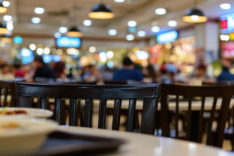Dark wooden chair at a table in a busy food court dining area
