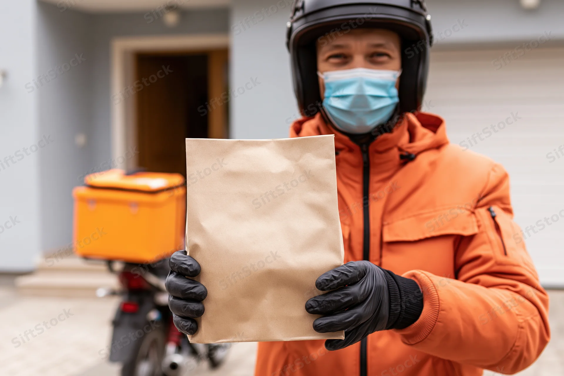 Delivery courier holding paper food bag in residential driveway