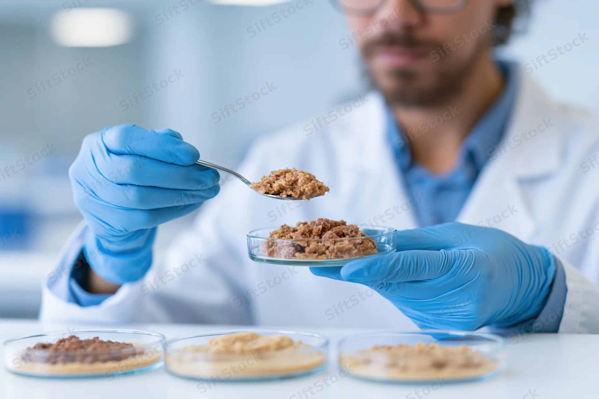 Scientist examining plant-based meat substitute sample in lab with spoon and petri dishes