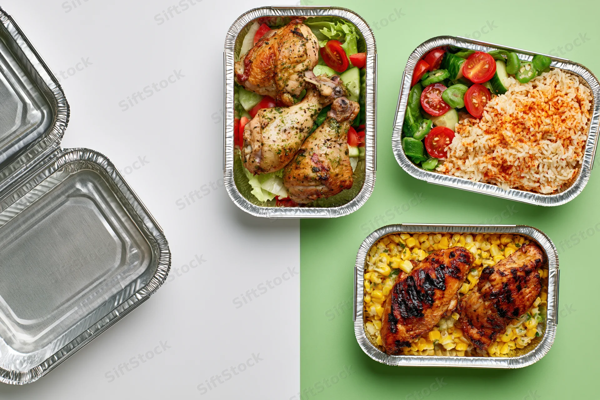 Four aluminum foil takeout containers with prepared meals arranged on white and green background