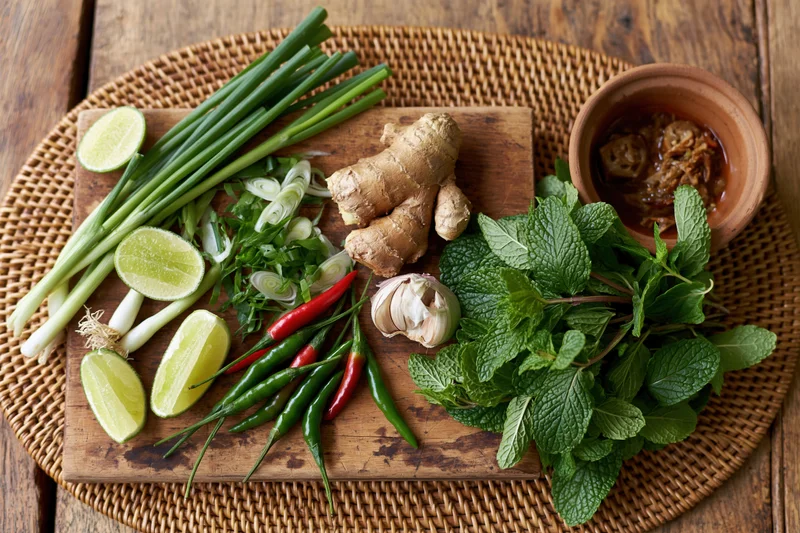 Vietnamese pho herbs and ingredients arranged on a wooden cutting board with wicker tray