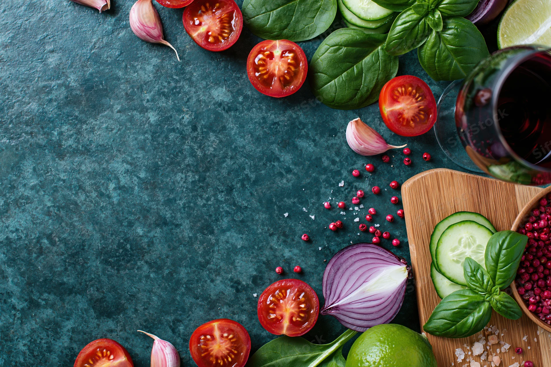 Fresh salad ingredients arranged around edges of dark surface with copyspace in center