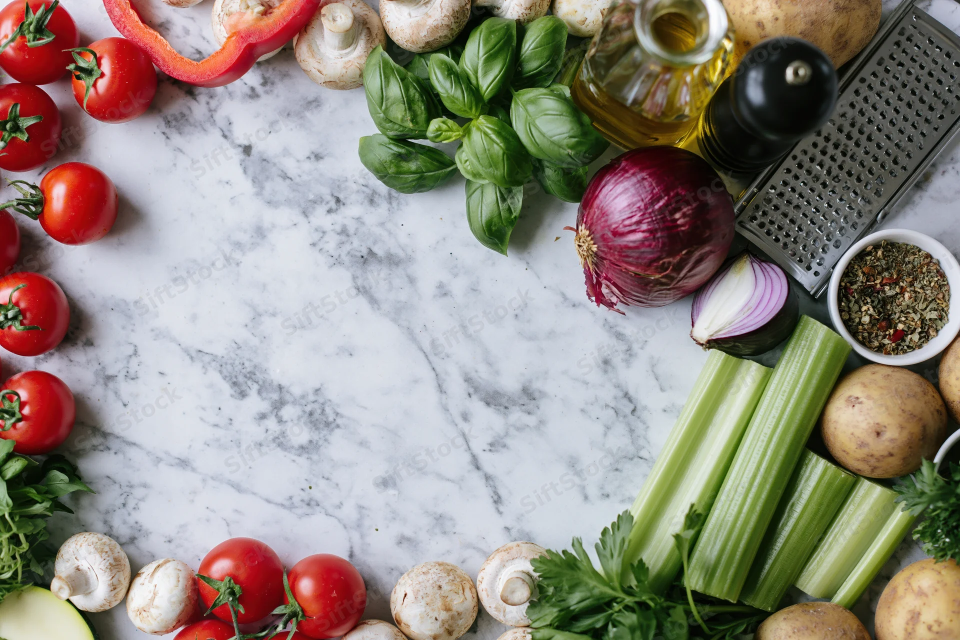 Fresh vegetables and herbs arranged as a border frame around a marble countertop with copyspace in center