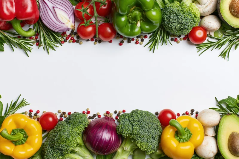 Fresh vegetables and herbs arranged in two horizontal borders on white background