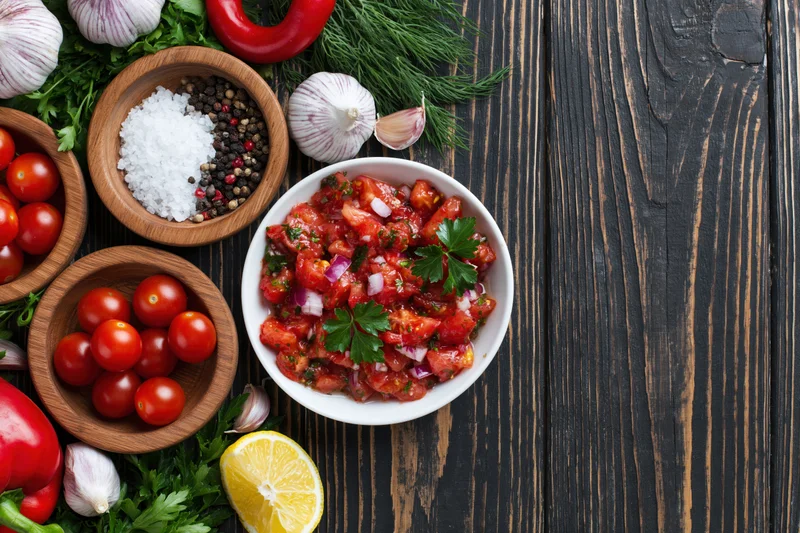 Fresh salad ingredients arranged on dark wooden table with copyspace on right