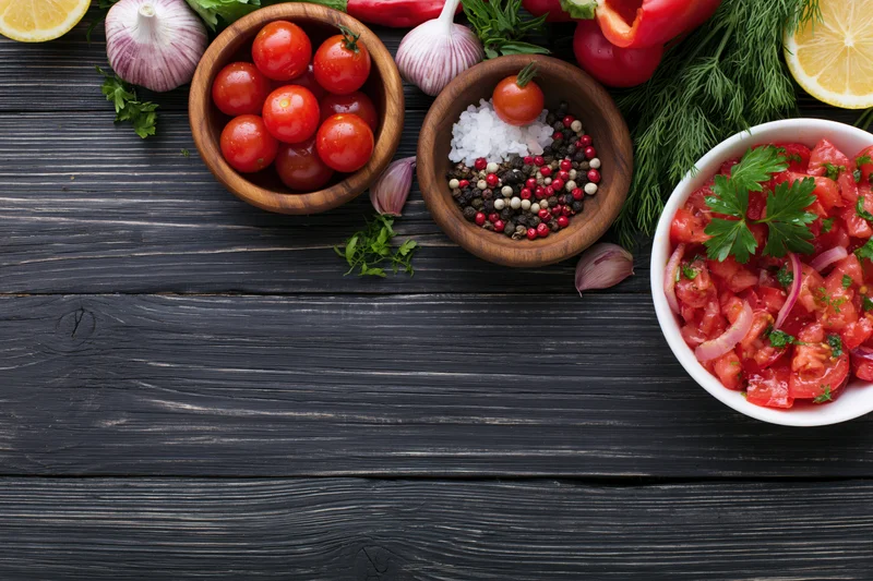 Fresh salad ingredients arranged on a dark wooden surface with copyspace