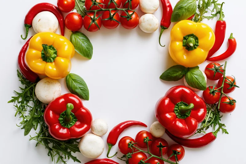 Fresh vegetables arranged in a circular frame on white background with copyspace