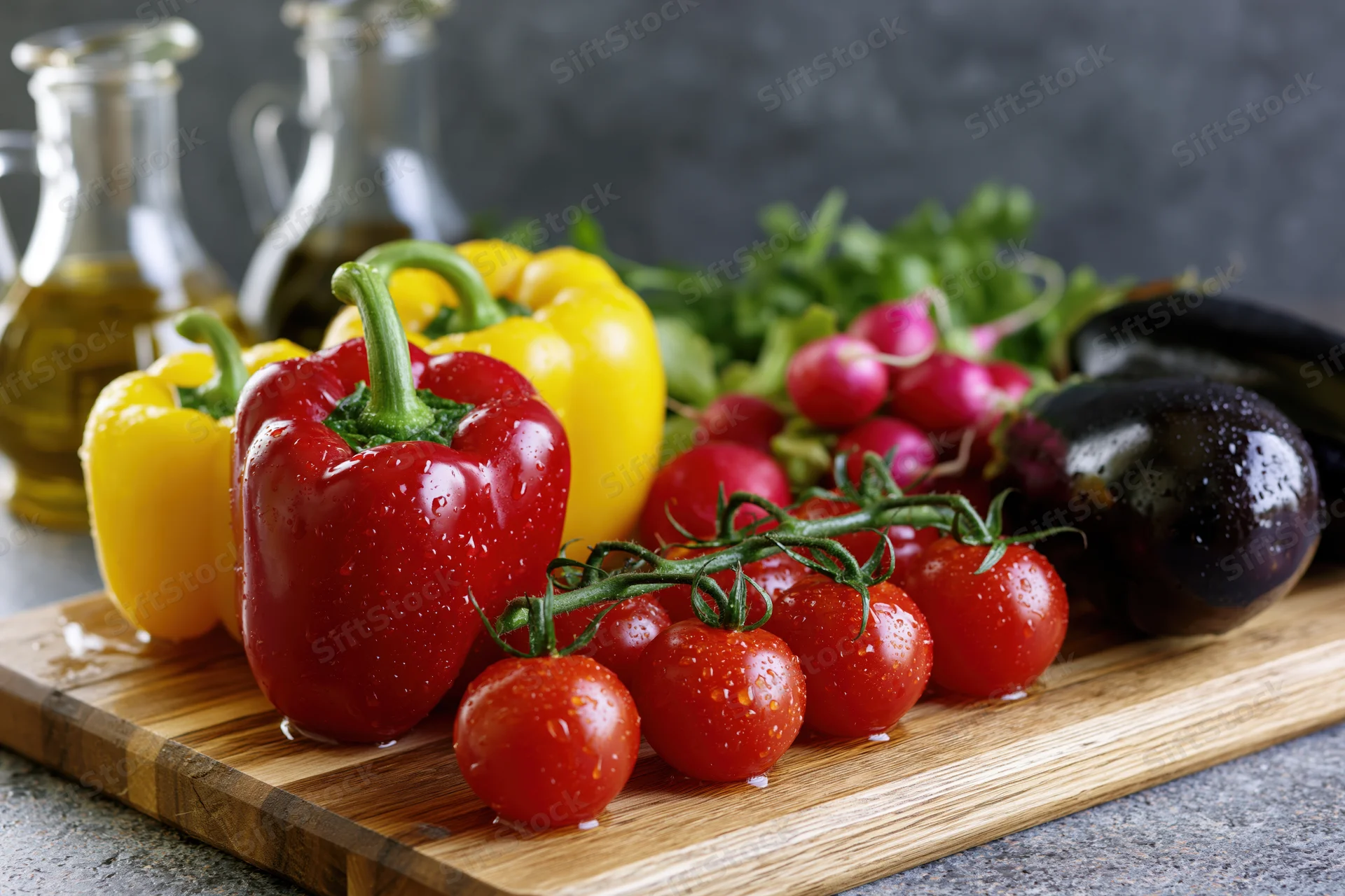 Fresh vegetables including bell peppers, tomatoes, eggplant and radishes arranged on a wooden cutting board in a kitchen setting