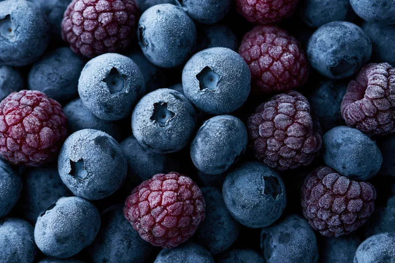 Frozen blueberries and raspberries tightly packed in a close-up view
