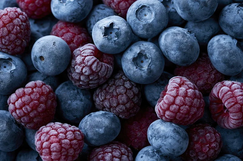 Frozen blueberries and raspberries tightly packed in a close-up view