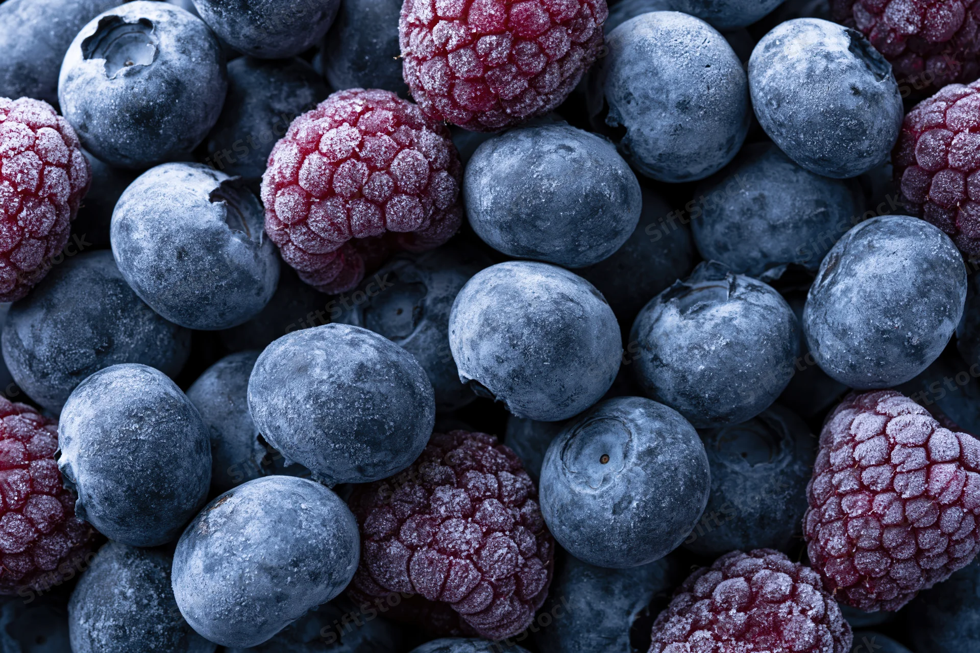 Frozen blueberries and raspberries tightly packed in a close-up view