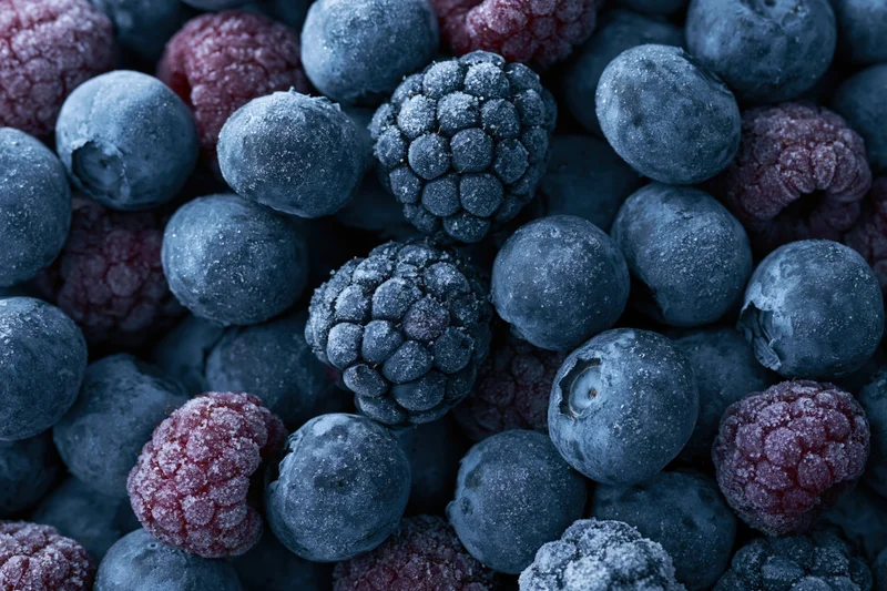 Frozen blueberries and raspberries tightly packed in a close-up view