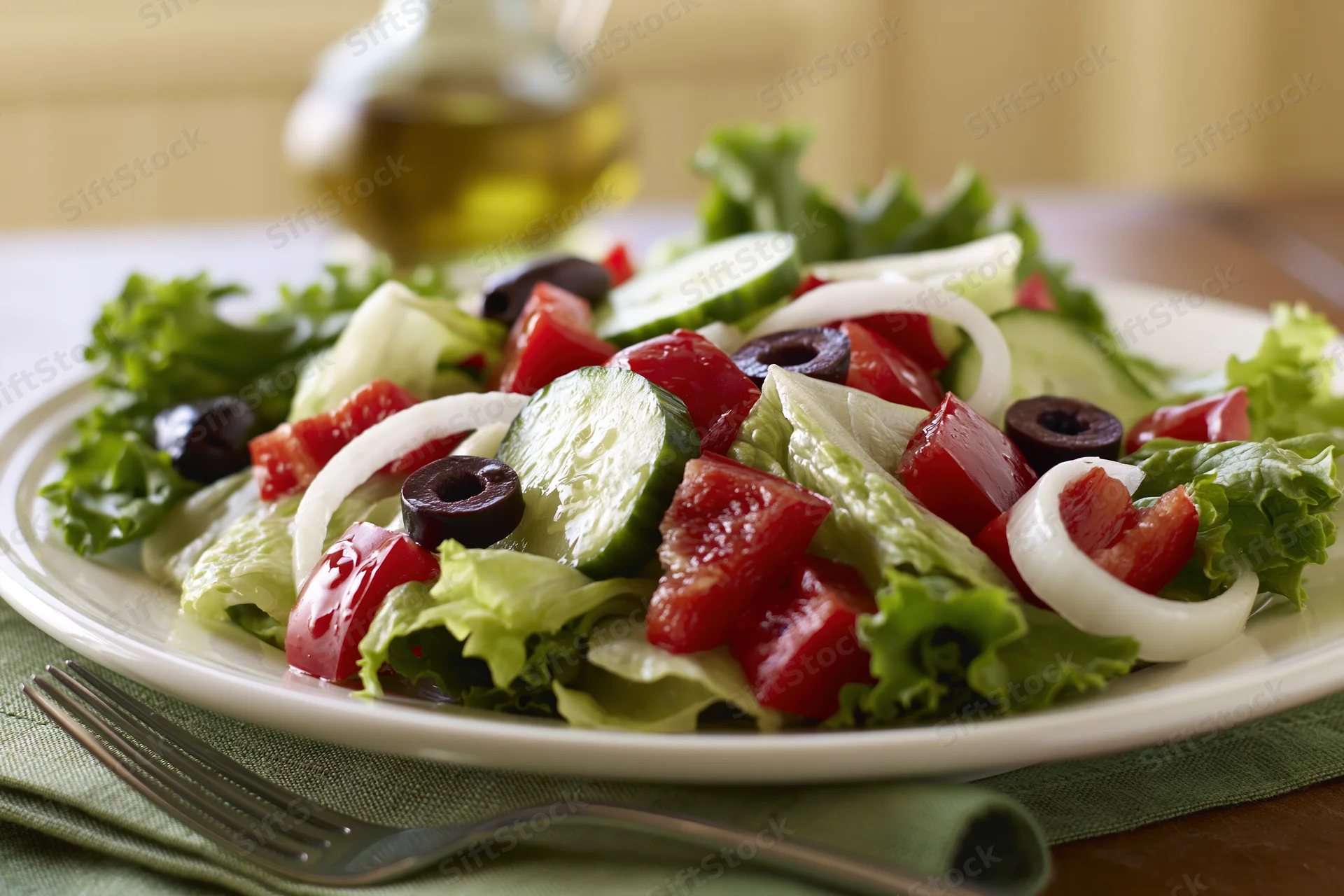 Greek-style salad with tomatoes cucumbers olives and onions on a white plate with fork and napkin on wooden table