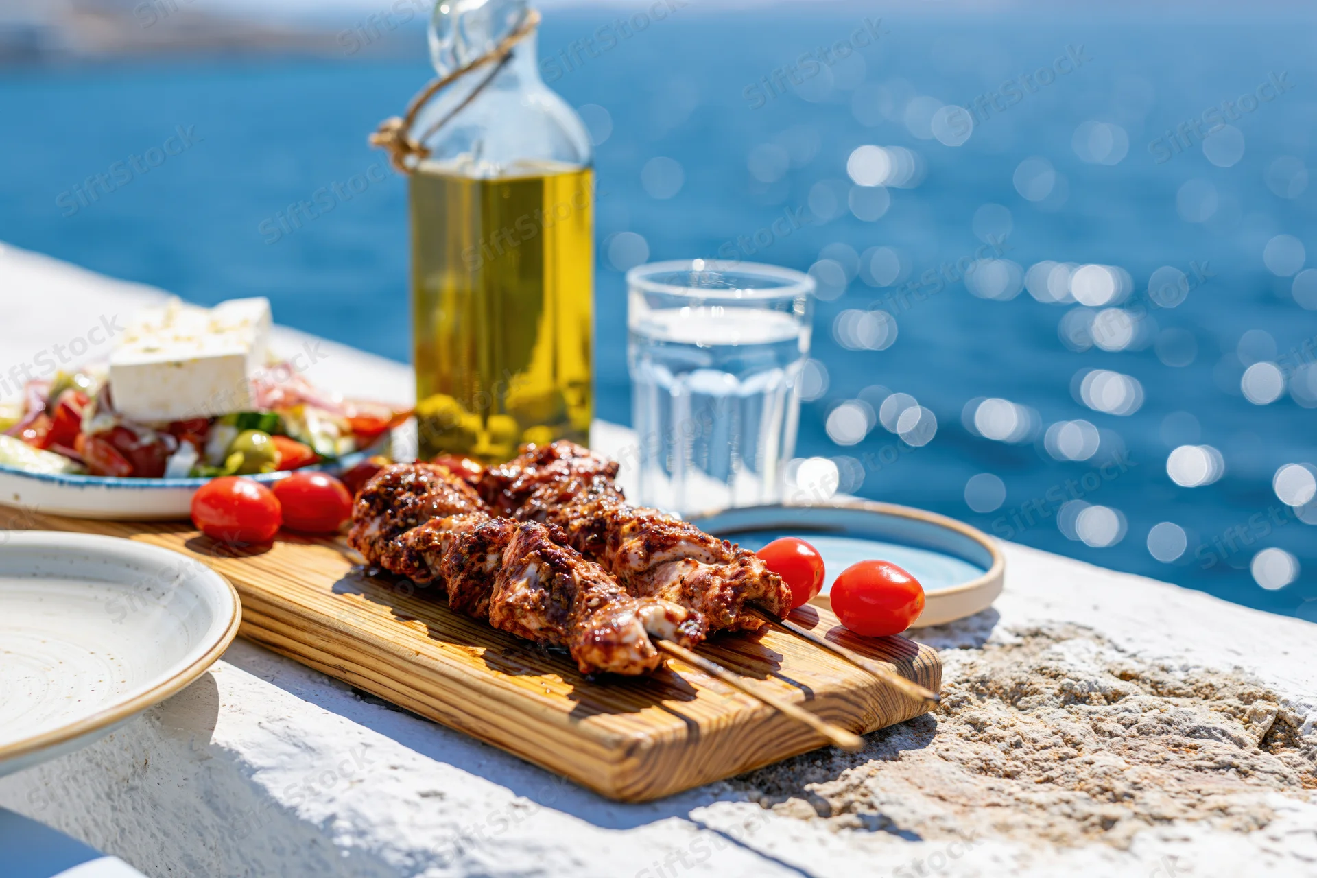 Grilled meat skewers and greek salad on a stone terrace by the ocean