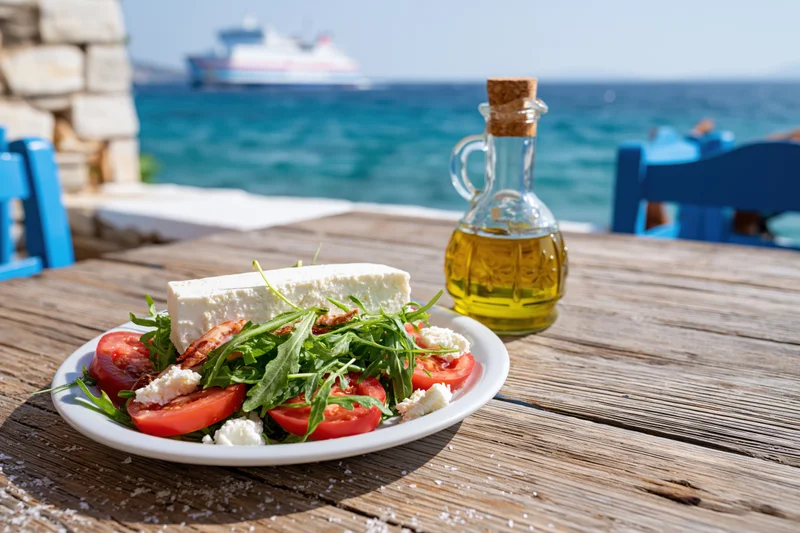 Greek salad with feta cheese and tomatoes on a wooden table by the sea